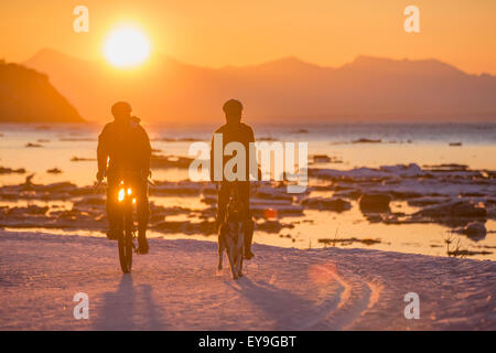 Matura in bicicletta in inverno al tramonto sul Percorso Costiero di Tony Knowles, Cook Inlet, centromeridionale Alaska Foto Stock