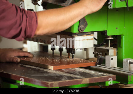 Carpenter lavora con professionisti macchina perforatrice in officina. Foto Stock