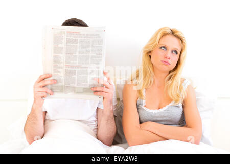 Vista di una giovane donna di annoiarsi mentre il suo ragazzo lettura notizie Foto Stock