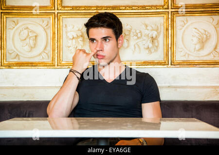La testa e le spalle del giovane attraente Man Picking naso con Pinky dito nella sala decorata con marmo bianco e oro incorniciato Ar Foto Stock
