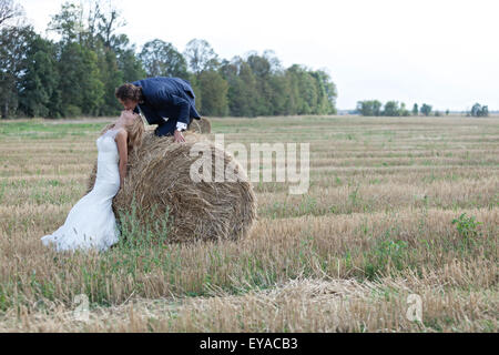 Bella coppia sposata che agisce molto romantico su un campo di balle. Egli si arrampica la balla a baciare le sue labbra mentre lei stabilisce la sua testa t Foto Stock