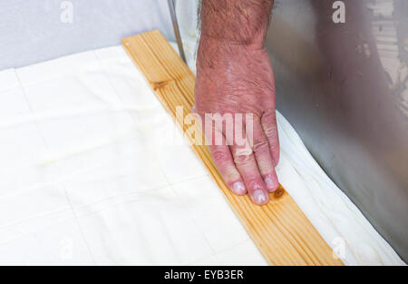 Il processo di produzione di gustosi piatti tradizionali bulgari bianco formaggio feta alla sua fase finale prima di pacchettizzazione. Tagliare a cubetti con un Foto Stock