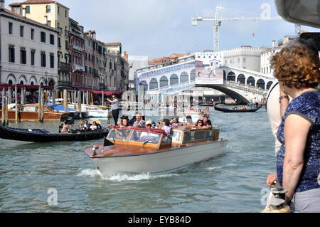 Italia - Venezia - Canale Grande - gondole acqua taxi occupato sullo sfondo della scena ponte di Rialto sole blu cielo Foto Stock
