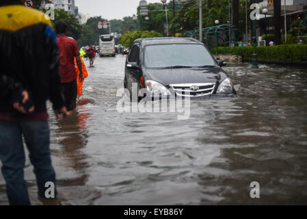 Un'auto che si muove attraverso una strada allagata, dopo una pioggia continua ha lasciato l'area del centro di Jakarta allagato. Foto Stock