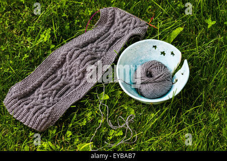 Fatte a mano sciarpa di lana e la sfera di filati di lana su sfondo di erba Foto Stock