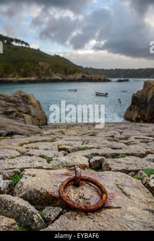 Di ferro arrugginito anello di ormeggio sulla pietra di uno scalo All Saints Bay Harbor, Guernsey, Isole del Canale. Foto Stock