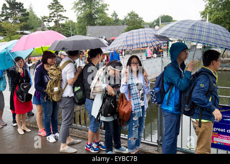 Lago di Windermere, Cumbria, Regno Unito. Il 26 luglio 2015. Regno Unito: Meteo Lago di Windermere. I turisti cinesi e i loro ombrelloni godetevi themsleves dispite la pioggia Bowness Bay Credito: Gordon Shoosmith/Alamy Live News Foto Stock