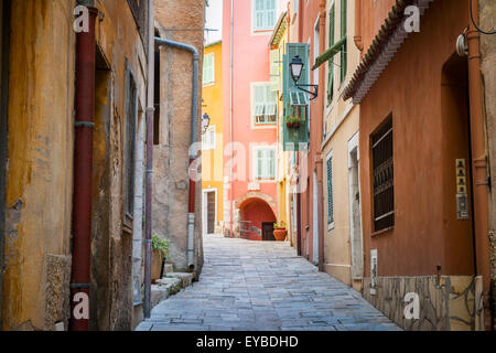 Stretta strada di ciottoli con luminosi edifici nella città medievale di Villefranche-sur-Mer sulla Costa Azzurra, Francia. Foto Stock