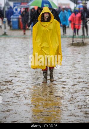 Malmesbury, Wiltshire, Regno Unito. 26 Luglio, 2015. Un festival goer passeggiate attraverso il fango e la pioggia a Womad Festival tenutosi a Charlton Park, nel Gloucestershire. Il 26 luglio 2015. Credito: Adam Gasson/Alamy Live News Foto Stock