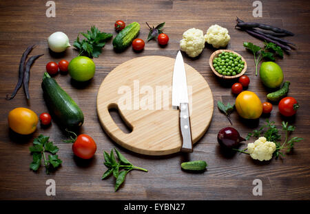 Fresche verdure organiche sulla tabella awooden con tagliere e coltello. Foto Stock