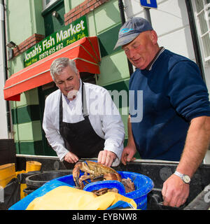 Acquisto di cibo locale: il proprietario di Giona il mercato del pesce, pescivendolo Craig Edwards, acquisto appena catturati e sbarcati Cardigan Bay granchi marrone da un pescatore, Aberystwyth Wales UK Foto Stock