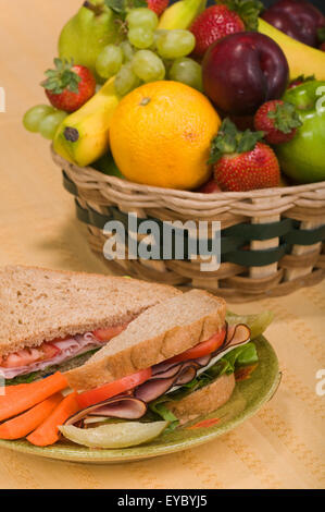 Panino su una piastra con una salamoia e i bastoncini di carote. Prosciutto su pane di segale panino con lattuga, pomodoro e formaggio Foto Stock