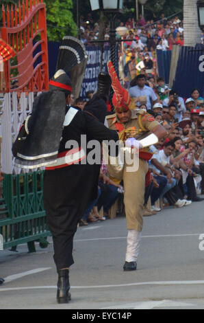 Rangers Pakistani (indossando divisa nera) e il confine indiano forza di sicurezza (BSF) durante una parata giornaliera al giunto Pakistan-India check-post a Wagah border. India e Pakistan solennemente abbassato le loro bandiere nazionali a un tramonto cerimonia militare sulla loro terra principale di attraversamento di confine. La bandiera di cerimonia di abbassamento è estremamente popolare su entrambi i lati, con folle ogni giorno fuori di imballaggio bleachers impostato su entrambi i lati delle gate ornato da grandi rivolta verso i ritratti dei loro padri fondatori, il Mahatma Gandhi sul lato indiano e Mohammed Ali Jinnah sul lato pakistano. (Foto di rana Sajid Hussain/Pa Foto Stock