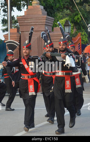 Rangers Pakistani (indossando divisa nera) e il confine indiano forza di sicurezza (BSF) durante una parata giornaliera al giunto Pakistan-India check-post a Wagah border. India e Pakistan solennemente abbassato le loro bandiere nazionali a un tramonto cerimonia militare sulla loro terra principale di attraversamento di confine. La bandiera di cerimonia di abbassamento è estremamente popolare su entrambi i lati, con folle ogni giorno fuori di imballaggio bleachers impostato su entrambi i lati delle gate ornato da grandi rivolta verso i ritratti dei loro padri fondatori, il Mahatma Gandhi sul lato indiano e Mohammed Ali Jinnah sul lato pakistano. (Foto di rana Sajid Hussain/Pa Foto Stock