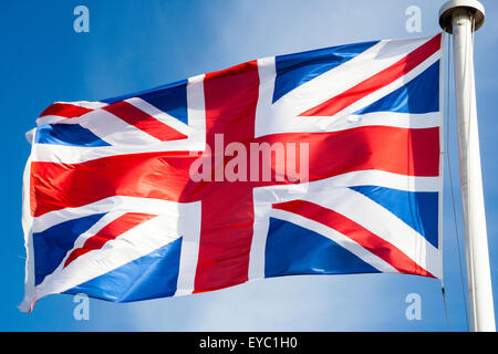 Britannica Union Jack bandiera e che fluttua nel vento sulla cima del pennone di bianco. Bianco e blu cielo dietro la bandiera. Foto Stock