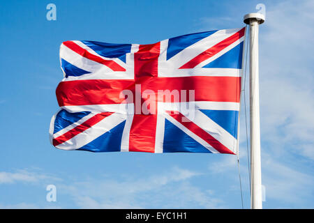 Britannica Union Jack bandiera e che fluttua nel vento sulla cima del pennone di bianco. Bianco e blu cielo dietro la bandiera. Foto Stock