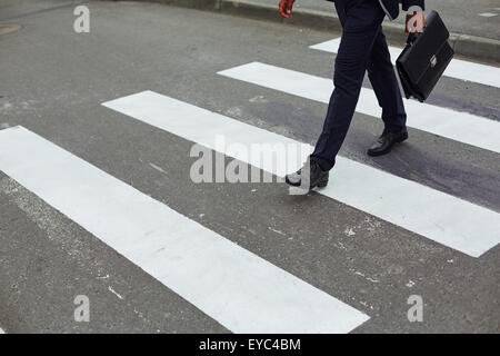 Elegante uomo d affari con valigetta camminando giù crosswalk Foto Stock
