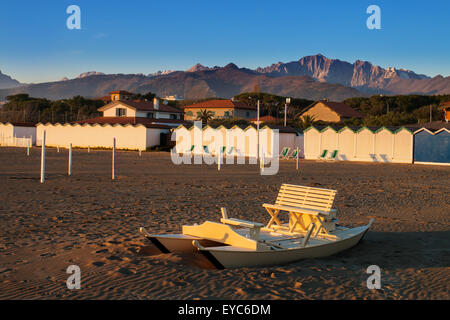 Remo in legno boat chiamato in Italia "pattino" o "oscone' mezzo sepolto dalla sabbia sulla spiaggia di Forte dei Marmi, cabina mare Foto Stock