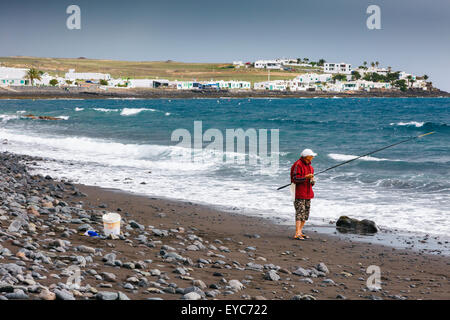 Il pescatore in una spiaggia sassosa. Playa, Quemada Yaiza. Lanzarote, Isole canarie, Spagna, Europa. Foto Stock