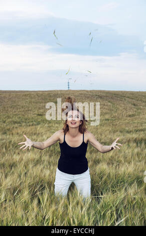 Giovane donna facendo salti pazzo in un campo di grano. Bellezza naturale. Foto Stock