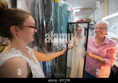 Broomfield, Colorado - una giovane donna cerca sul suo incompiuto abito da sposa come sua madre orologi. Foto Stock