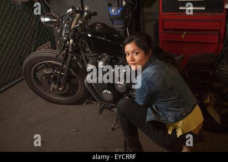 Meccanico femmina a lavorare sulla moto in officina Foto Stock