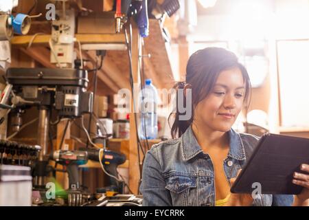 Meccanico femmina con tavoletta digitale in officina Foto Stock