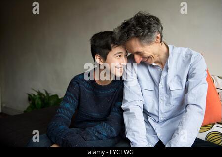 Ragazzo adolescente e padre faccia a faccia sul divano Foto Stock