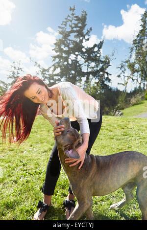 Giovane donna petting il suo cane in posizione di parcheggio Foto Stock