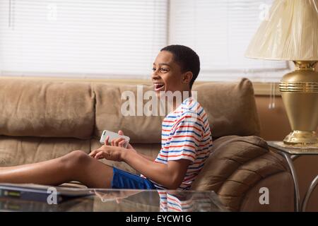 Ragazzo adolescente seduti sul divano a ridere Foto Stock