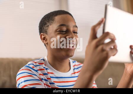 Ragazzo adolescente che posano per una tavoletta digitale selfie sul divano Foto Stock