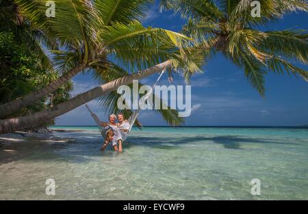 Coppia senior relax in amaca, Maldive Foto Stock