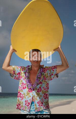 Senior man tenendo la tavola da surf, ritratto Foto Stock