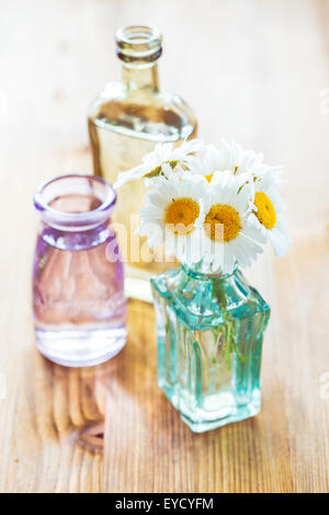 Bouquet di chamomiles in piccoli vasetti di vetro su sfondo di legno Foto Stock