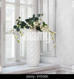 Ancora in vita con bouquet di artificiale fiori di ciliegio in un vaso cinese sul davanzale in bianco interiour Foto Stock