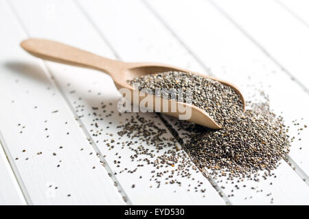 Semi di chia nel convogliatore di legno sul tavolo bianco Foto Stock