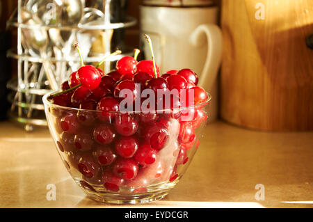 Vaso di vetro pieno di red ciliegie mature sul tavolo Foto Stock