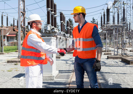 Due ingegneri si stringono la mano dalla sottostazione elettrica Foto Stock