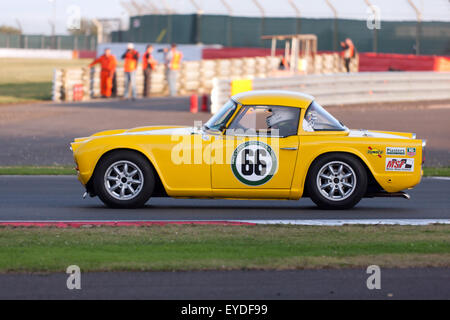 Michael Pearson guida di un giallo 1964, Triumph TR4, nel trofeo internazionale di gara per le classiche vetture GT (pre' 1966) a Silverstone Classic 2015 Foto Stock