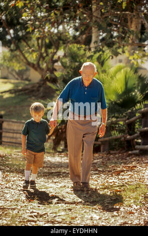 Un uomo anziano e i suoi cinque anni di nipote camminare insieme su un sentiero in Lake Forest, CA, in un pomeriggio soleggiato. Foto Stock