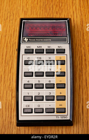 Vintage Texas Instruments Ti-1250 elettronico di base calcolatrice matematica introdotta nel 1975 su una vecchia scrivania in legno Foto Stock