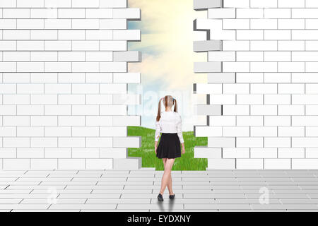 Schoolgirl guardando fatiscenti e parete di mattoni Foto Stock