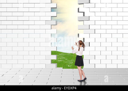 Schoolgirl guardando fatiscenti e parete di mattoni Foto Stock