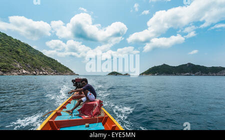 Local uomo seduto a poppa, sterzo una longtail boat nel mare turchese, isola di Koh Tao, Golfo di Thailandia, Tailandia Foto Stock