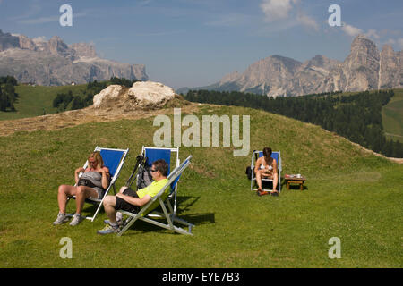 Prendere il sole gli escursionisti in sedie a sdraio in Pralongià sopra San Cassiano-St. Cassiano nelle Dolomiti, Alto Adige, Italia settentrionale. In inverno il Pralongià prati sono il cuore di Alta Badia il comprensorio sciistico. Foto Stock