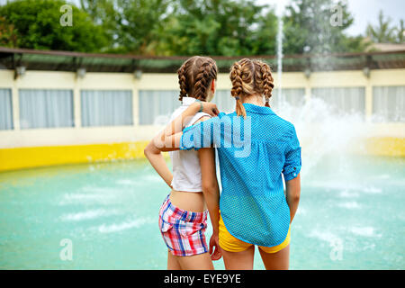 Migliori amiche stare vicino alla fontana in estate park. Ragazze vestito in pantaloncini corti e una maglietta. Le vacanze estive. Il concetto di Foto Stock