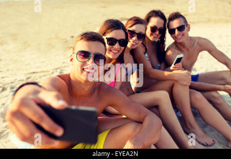 Gli amici con gli smartphone sulla spiaggia Foto Stock