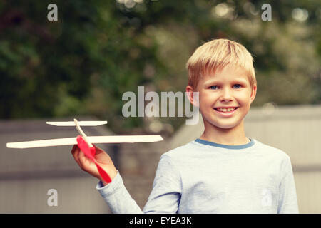 Sorridente ragazzino tenendo un legno modello di aeroplano Foto Stock