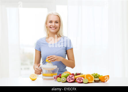 Donna sorridente spremendo il succo di frutta a casa Foto Stock
