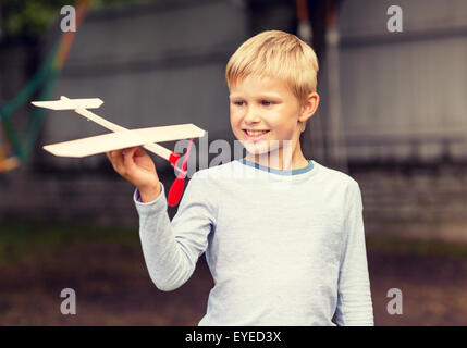 Sorridente ragazzino tenendo un legno modello di aeroplano Foto Stock